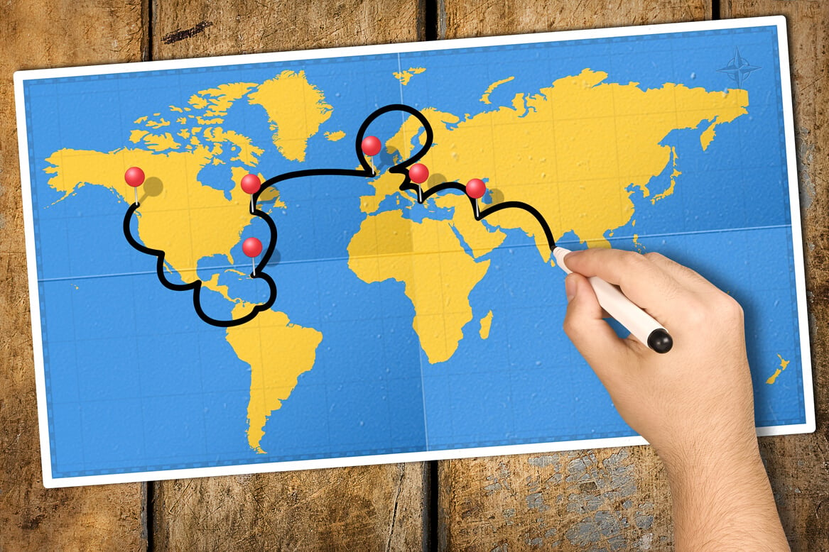 Hand tracking travel itinerary with black felt tip or marker on world map